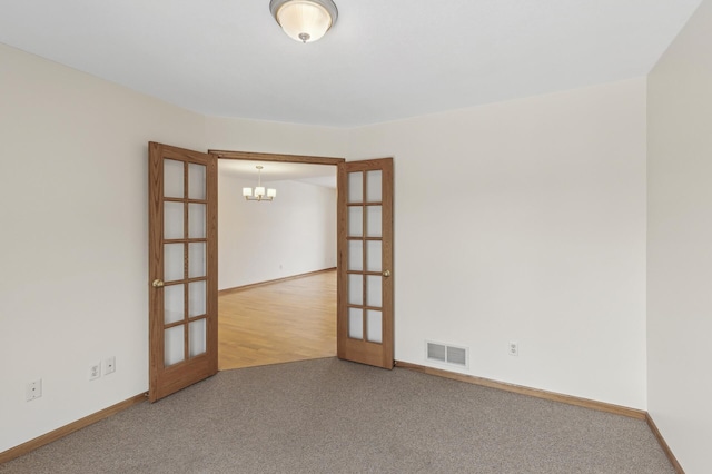 spare room featuring carpet, a chandelier, and french doors