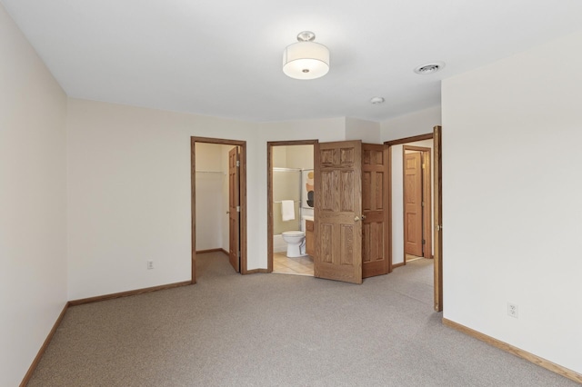 unfurnished bedroom featuring light carpet, a spacious closet, connected bathroom, and a closet