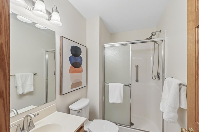 bathroom featuring vanity, a shower with shower door, and toilet