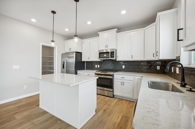 kitchen with light wood-style flooring, a sink, white cabinetry, appliances with stainless steel finishes, and a center island