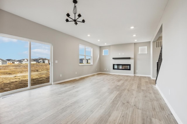 unfurnished living room featuring light wood-style flooring, recessed lighting, visible vents, baseboards, and a glass covered fireplace