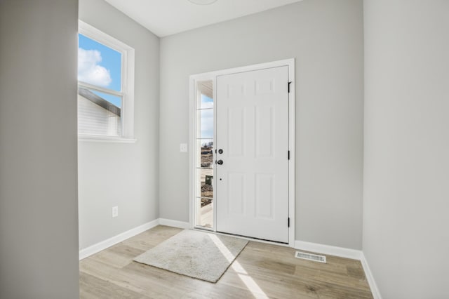 foyer entrance featuring light wood-style flooring, visible vents, and baseboards