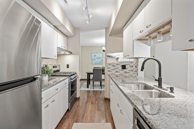 kitchen with light stone countertops, appliances with stainless steel finishes, white cabinets, and sink