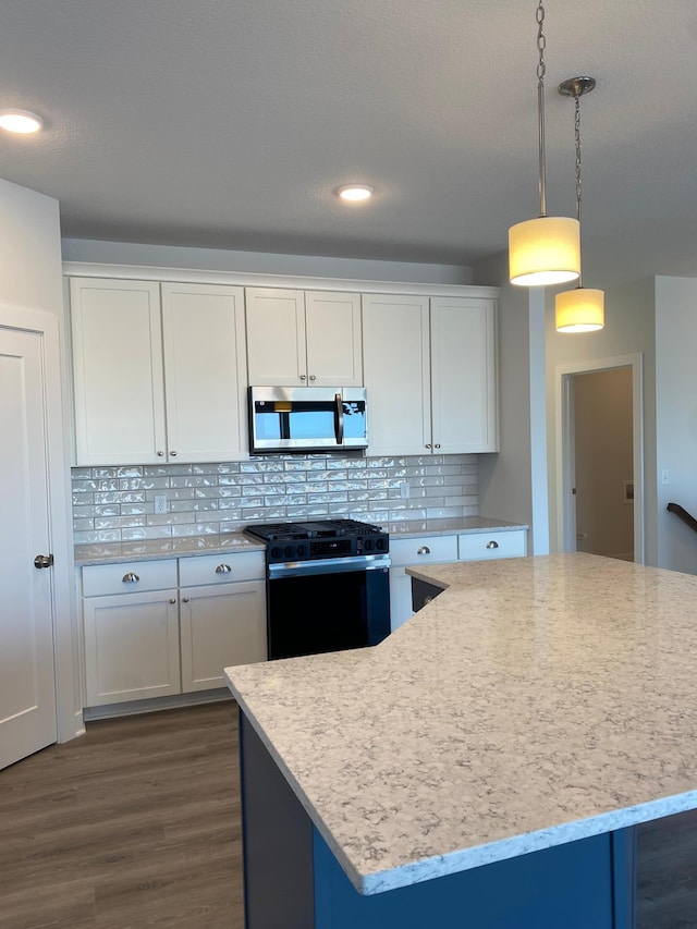 kitchen with a kitchen island, decorative light fixtures, white cabinetry, tasteful backsplash, and black range with gas stovetop