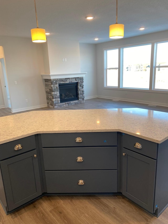 kitchen featuring decorative light fixtures, a fireplace, gray cabinetry, and light hardwood / wood-style floors