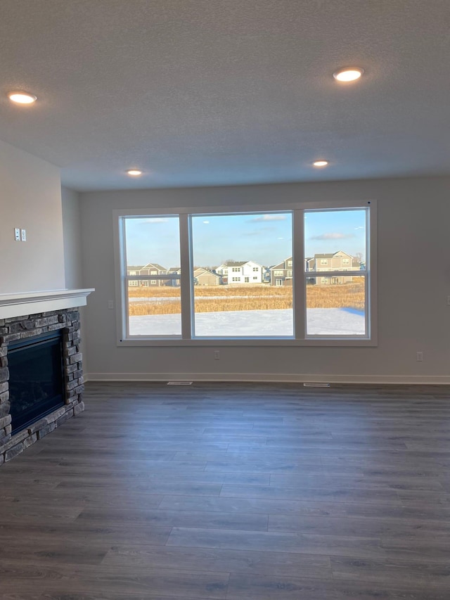 unfurnished living room with a wealth of natural light, dark hardwood / wood-style flooring, and a fireplace