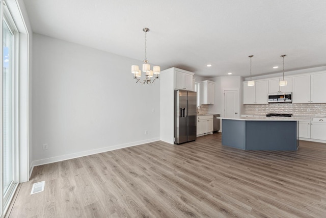 kitchen featuring pendant lighting, white cabinetry, stainless steel appliances, and backsplash