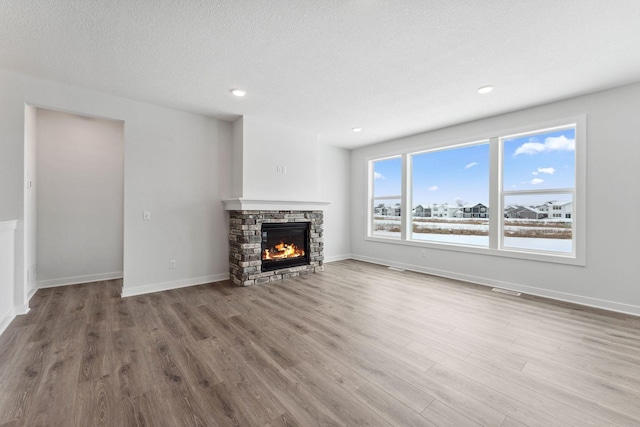 unfurnished living room with hardwood / wood-style flooring, a textured ceiling, and a fireplace