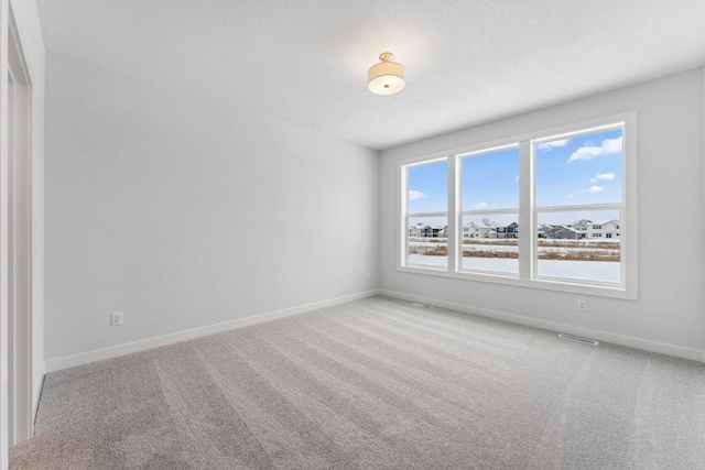 spare room with light carpet and a textured ceiling