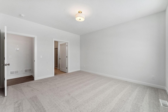 unfurnished bedroom featuring light colored carpet and a walk in closet