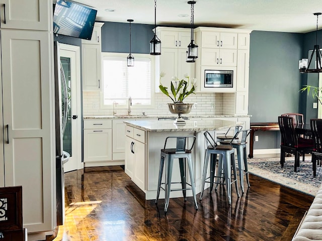 kitchen featuring sink, a center island, stainless steel microwave, and hanging light fixtures