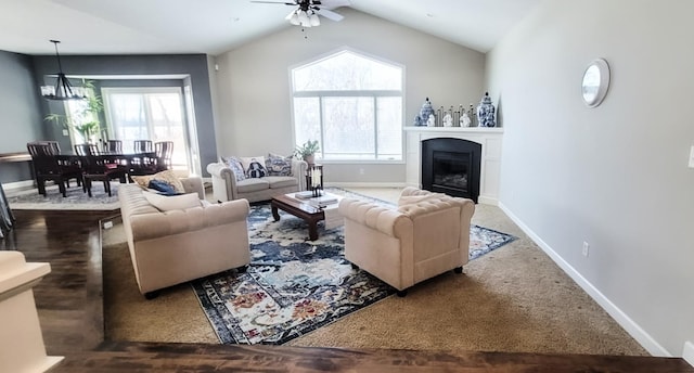 carpeted living room featuring ceiling fan with notable chandelier, vaulted ceiling, and a wealth of natural light