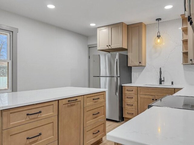 kitchen with sink, stainless steel fridge, hanging light fixtures, light hardwood / wood-style floors, and light brown cabinets