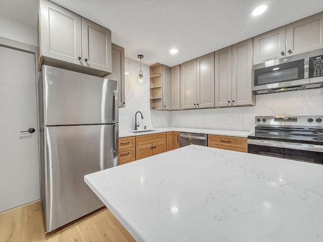 kitchen featuring sink, light hardwood / wood-style flooring, appliances with stainless steel finishes, backsplash, and decorative light fixtures