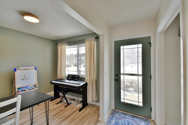 entrance foyer with light wood-style flooring, a textured ceiling, and baseboards