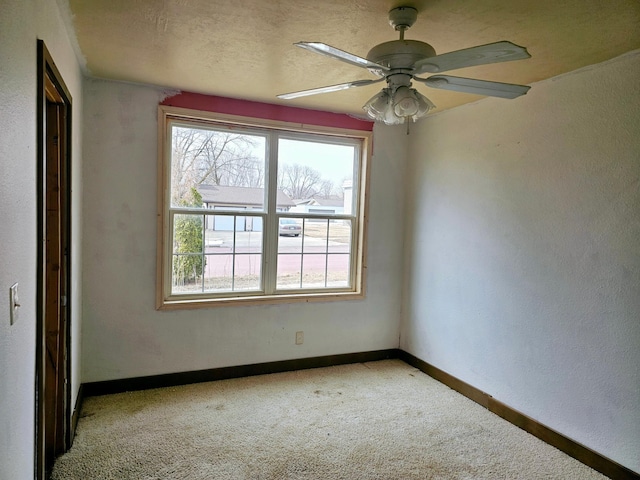 spare room with ceiling fan, a textured ceiling, baseboards, and light carpet