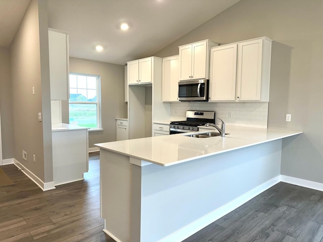 kitchen with kitchen peninsula, stainless steel appliances, vaulted ceiling, white cabinets, and sink