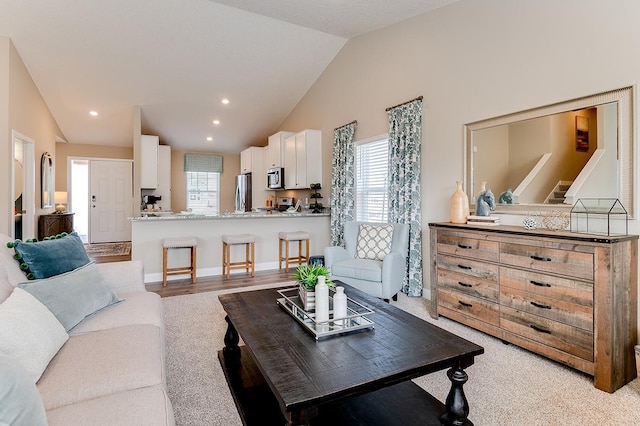 living room with high vaulted ceiling and light carpet