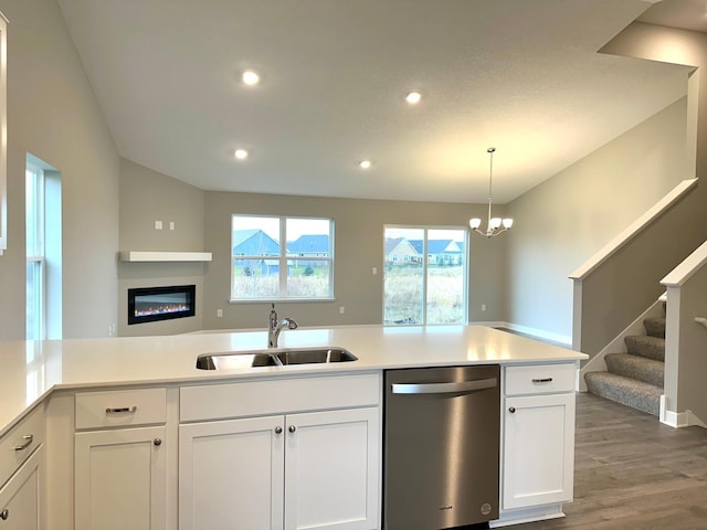 kitchen with white cabinets, decorative light fixtures, wood-type flooring, sink, and stainless steel dishwasher