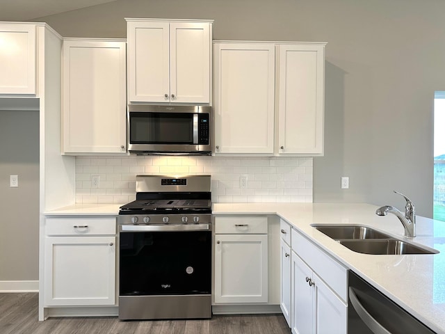 kitchen with backsplash, sink, hardwood / wood-style flooring, appliances with stainless steel finishes, and white cabinets