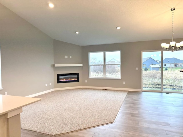 unfurnished living room featuring light wood-type flooring and an inviting chandelier