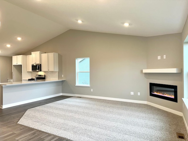 kitchen with kitchen peninsula, appliances with stainless steel finishes, backsplash, dark hardwood / wood-style flooring, and white cabinets