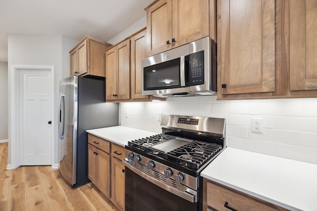 kitchen with tasteful backsplash, appliances with stainless steel finishes, and light wood-type flooring