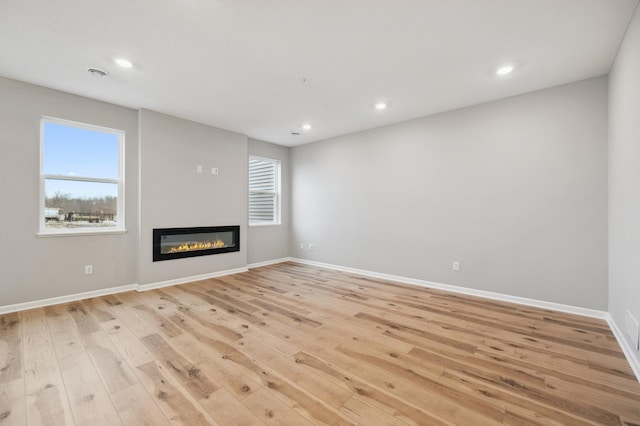 unfurnished living room featuring a wealth of natural light and light hardwood / wood-style flooring