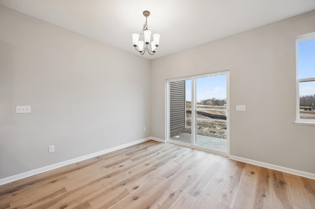 empty room featuring a notable chandelier and light hardwood / wood-style floors