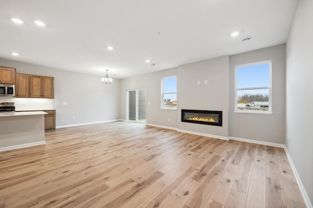 unfurnished living room with a notable chandelier and light wood-type flooring