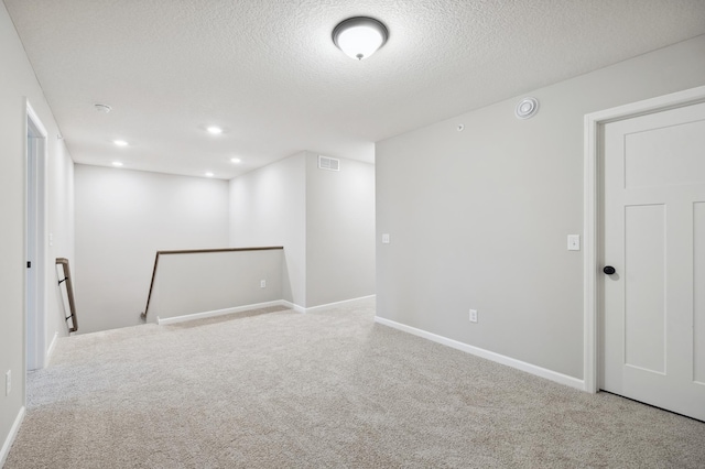 carpeted spare room featuring a textured ceiling