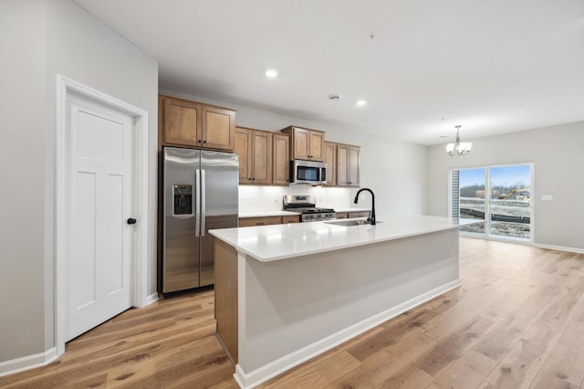 kitchen with a sink, recessed lighting, stainless steel appliances, light wood-style floors, and a chandelier