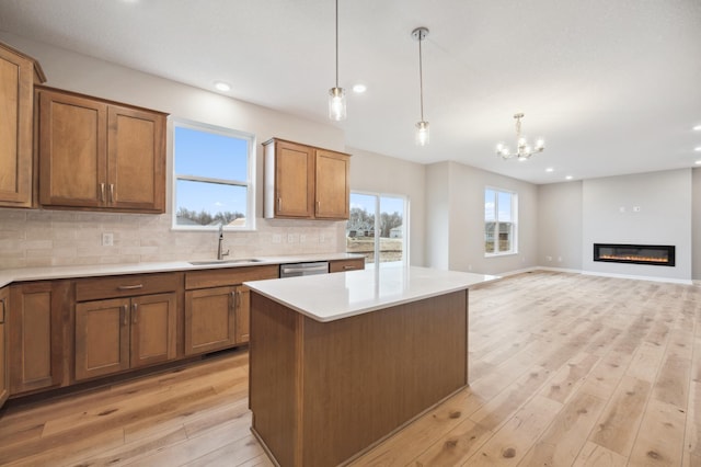 kitchen with pendant lighting, sink, a kitchen island, decorative backsplash, and light wood-type flooring