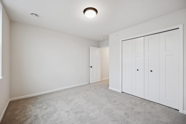 unfurnished bedroom with light carpet and a closet