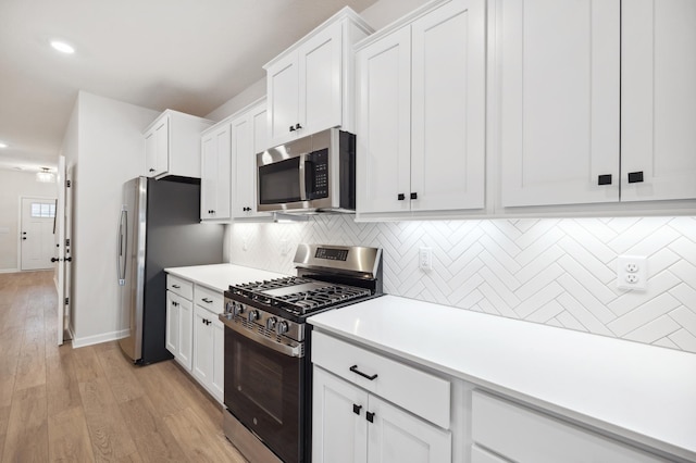 kitchen featuring tasteful backsplash, white cabinetry, stainless steel appliances, and light countertops