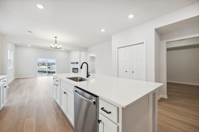 kitchen with dishwasher, light countertops, light wood-style floors, and a sink