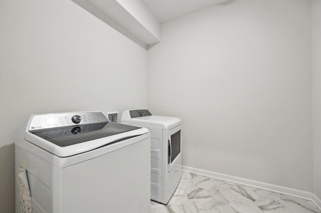 laundry room with baseboards, marble finish floor, washing machine and dryer, and laundry area