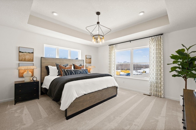 carpeted bedroom featuring a textured ceiling, an inviting chandelier, and a tray ceiling