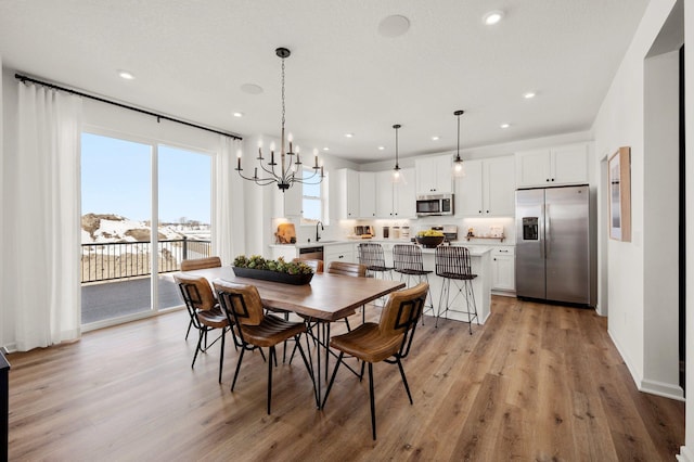 dining space featuring sink, an inviting chandelier, and light hardwood / wood-style flooring