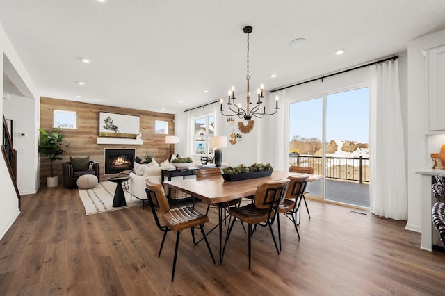 dining area with plenty of natural light, dark hardwood / wood-style floors, a chandelier, and wood walls