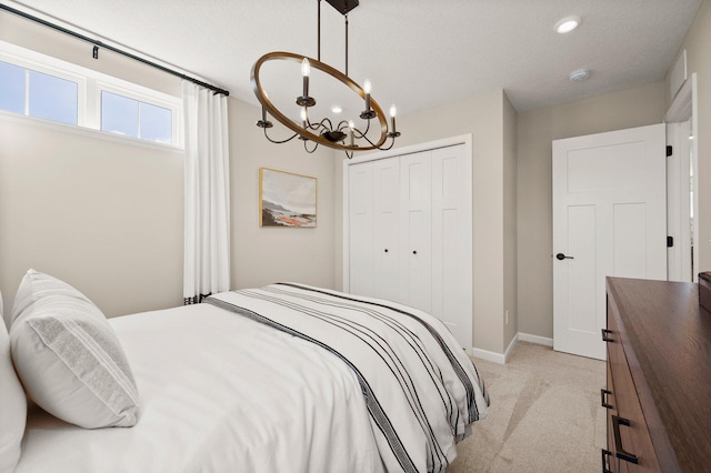 carpeted bedroom with an inviting chandelier, a closet, and a textured ceiling