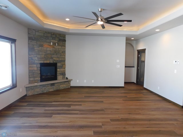 unfurnished living room featuring dark wood-type flooring, a fireplace, and a raised ceiling