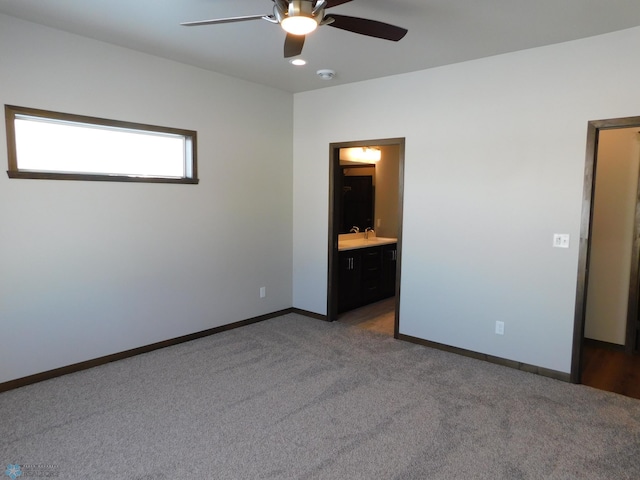 unfurnished bedroom with ceiling fan, ensuite bath, sink, and dark carpet