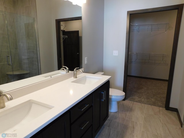 bathroom featuring a shower with door, vanity, and toilet