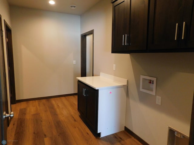 laundry room featuring washer hookup, light hardwood / wood-style floors, and cabinets