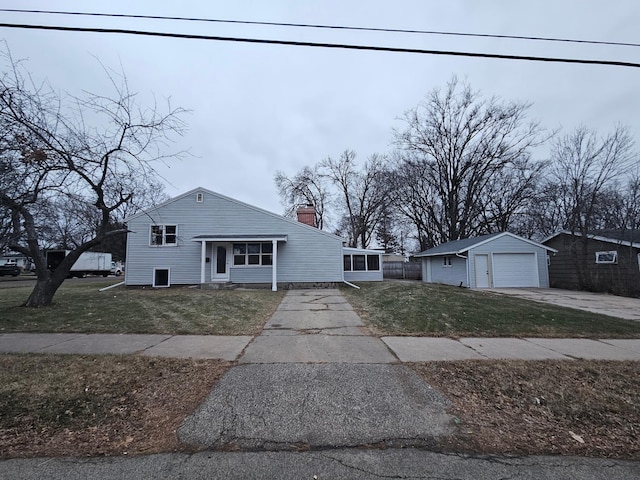 view of front of property featuring a garage, a sunroom, an outbuilding, and a front yard