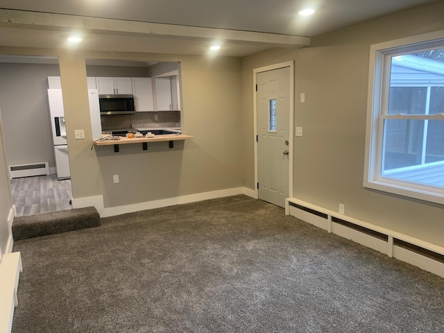 kitchen with white cabinetry, a baseboard radiator, white fridge with ice dispenser, and tasteful backsplash