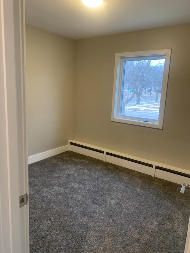 carpeted empty room featuring baseboard heating