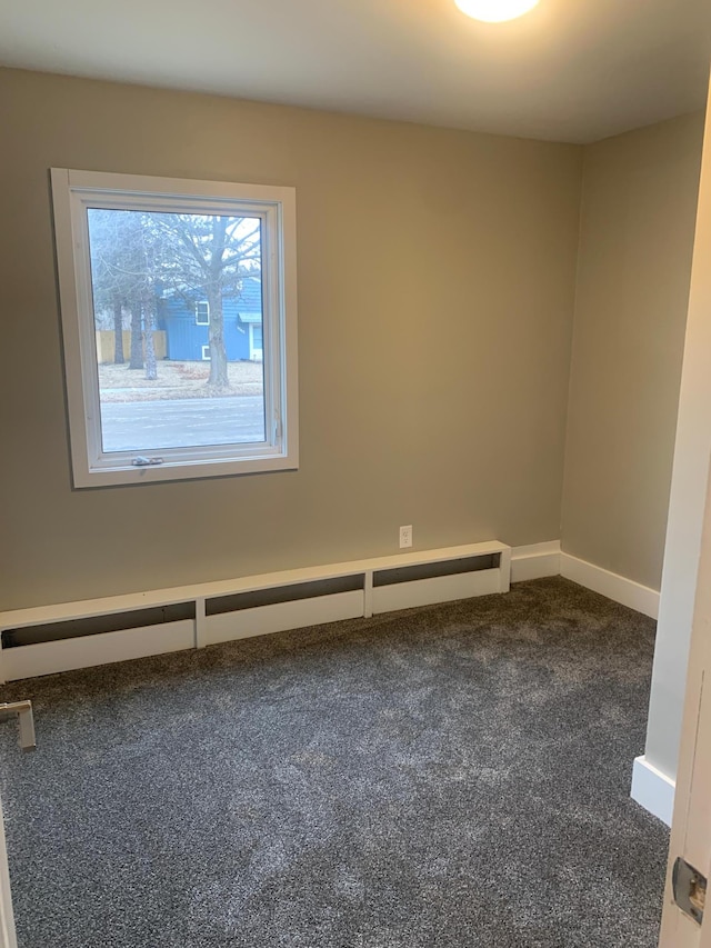 spare room with a baseboard radiator and dark carpet