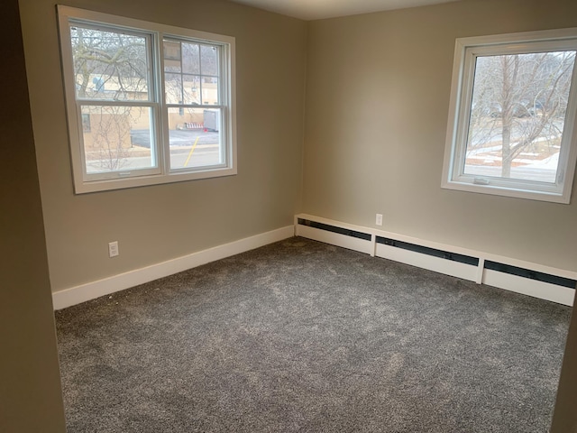 unfurnished room featuring baseboard heating, a healthy amount of sunlight, and dark carpet